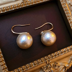 Vue détaillée de boucles d'oreilles dorées avec perles champagne texturées en cadre