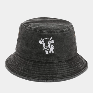 Detail of a black washed denim bucket hat featuring an embroidered white cow head design