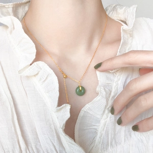 Close-up of a green Hetian jade Pingan buckle pendant on a gold 18K plated necklace