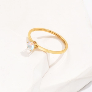 Detail of minimalist 1mm gold titanium ring featuring a single sparkling opal accent