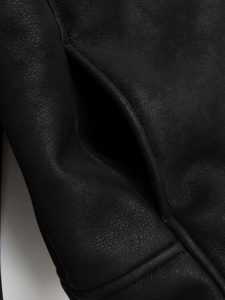 Close-up of black faux suede jacket pockets featuring detailed stitching and premium leather texture