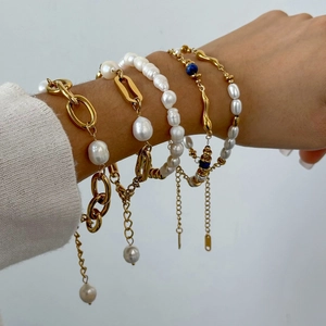 Elegant gold chain bracelet set with freshwater pearls and blue gemstone on wrist