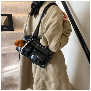 Close-up of black retro pillow bag with buckled pockets and plush puppy charm