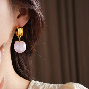 Detail of pink resin pendant earring with gold plating worn on model's earlobe