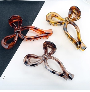 Detailed close-up of bow-shaped hair claws in tortoiseshell and marble patterns