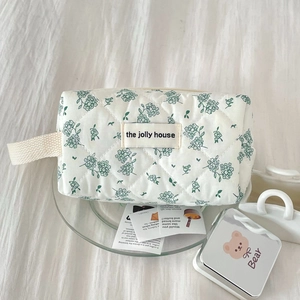 Quilted floral makeup bag with green star flowers on white fabric for travel storage
