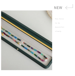 Detailed view of natural pearls and colorful gemstones inside a green jewelry box