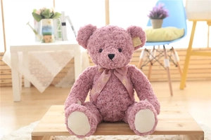 Detail of pink curly plush teddy bear with floral bow tie and premium fur texture
