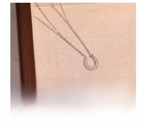 Macro shot of silver U-shaped titanium steel necklace with sparkling cubic zirconia inlay