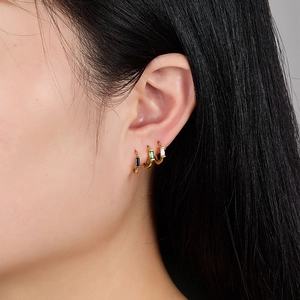 Detailed view of three gold S925 silver earrings with colorful zircon gems worn on an ear
