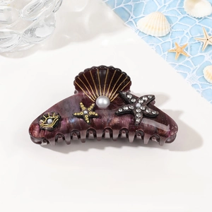 Detail of shell-shaped hair claw with pearls and rhinestones on ocean theme background