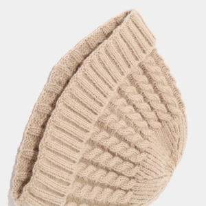 Close-up of beige chunky cable knit pattern and ribbed texture on winter beanie hat