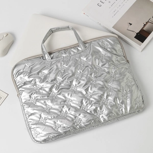 Detailed close-up of silver quilted laptop bag with elegant bow pattern stitching