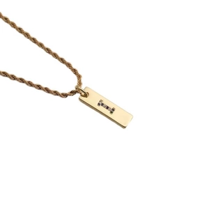 Detailed macro view of a gold rectangle pendant with dark gemstone letter I on twist chain