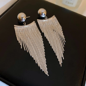 Detailed view of silver metal tassel earrings with spherical studs on black leather