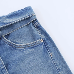 Gros plan du short en jean bleu montrant les détails de taille, les rivets et les coutures