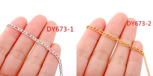 Detail of silver and 18k gold plated stainless steel Figaro chains held in hand