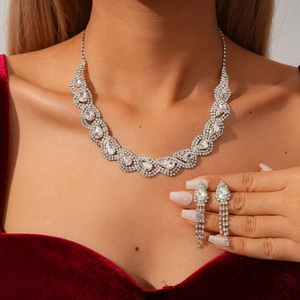 Detail view of silver pear-cut rhinestone necklace and fringe earrings set on a red velvet dress
