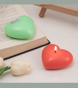Macro shot of heart-shaped scented candles in mint green and coral red on a shelf
