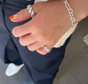 Detail view of sterling silver star ring and twisted rope band on hand with knitwear