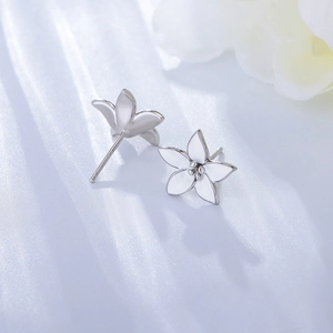 Detailed view of silver five-petal flower stud earrings with white enamel on silk