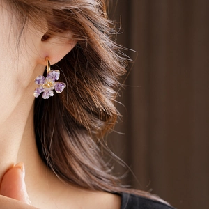 Close-up of vintage purple floral crystal earrings worn on model for an elegant look