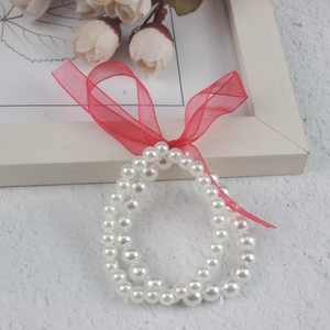 Double-layer white pearl bracelet for girls featuring a decorative red ribbon bow detail
