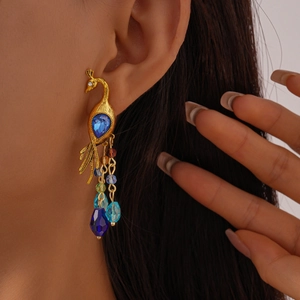 Close-up of vintage gold peacock earrings with blue rhinestones and beaded tassels