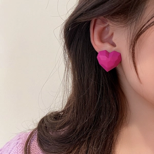 Minimalist candy pink heart stud earrings with geometric faceted cut on a female model