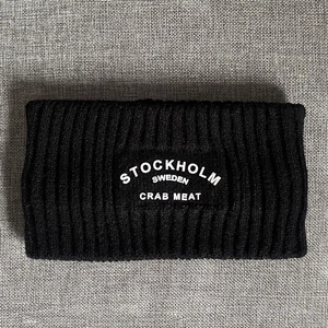 Nahaufnahme des schwarzen Rippstrick-Stirnbands mit weißem Stockholm-Schriftzug