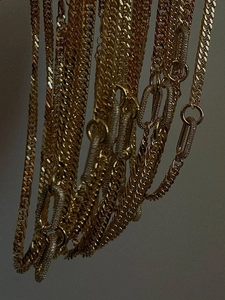 Detailed view of layered golden geometric choker chains with micro-pave rectangular clasps