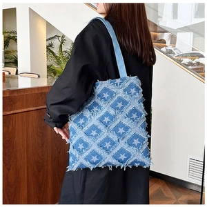Retro denim tote bag featuring star patterns and frayed edges worn by a model
