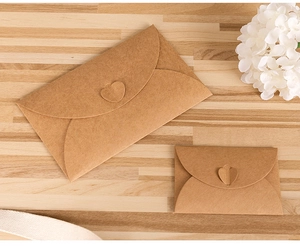 Flat lay of vintage kraft paper envelopes with heart closures on a wood texture background