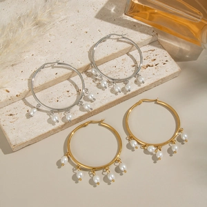 Elegant gold and silver hoop earrings with hanging pearls on a stone backdrop
