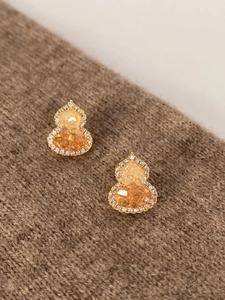 Detail of gold plated gourd earrings with amber resin and sparkling zircon inlay