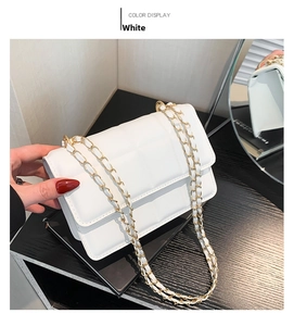 Detail of white quilted crossbody bag with golden chain strap and rhombus pattern texture