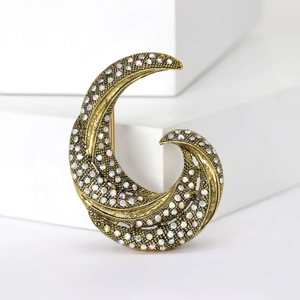 Macro shot of vintage golden leaf brooch with colorful rhinestones on a white background