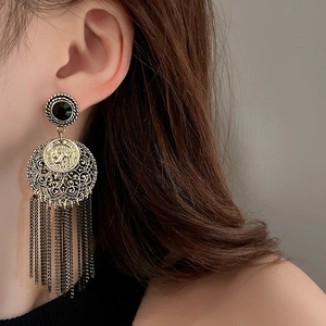 Close-up of bohemian tassel earrings with portrait relief and black gemstone studs