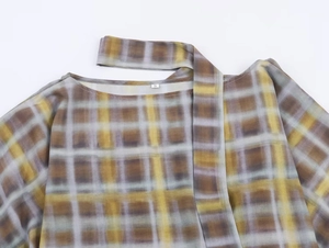 Détail de l'étiquette taille S sur un tissu à carreaux marron et jaune texturé
