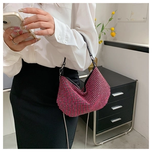 Detail showing pink rhinestone shoulder bag with metal chain on model with white shirt