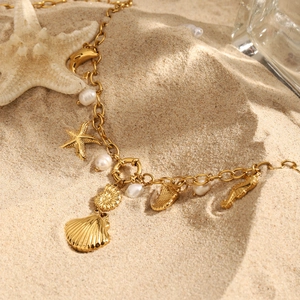 Gros plan d'un collier en acier titane doré avec pendentifs étoile de mer et perles