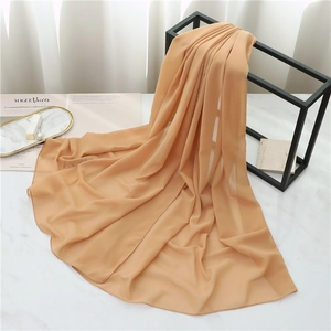 Detail view of light orange chiffon scarf hanging elegantly in a stylish lifestyle setting