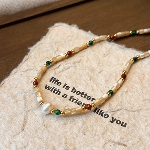 Macro shot of baroque pearl necklace with colorful beads on a vintage paper background