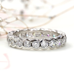 Macro detail of silver eternity ring featuring circular stones and scalloped bezel edge