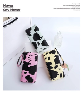 Cow print long zip wallets in mint, pink and beige with wrist straps on white display