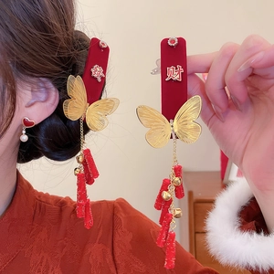 Detail of red velvet butterfly hair clips with golden bells and firecracker tassels