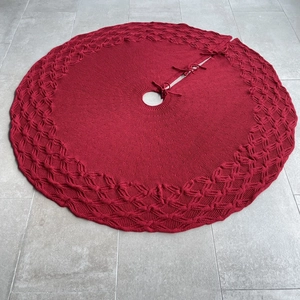Detailed top view of a red knitted Christmas tree skirt with intricate hollow patterns