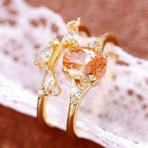 Close-up of champagne zircon ring set with oval gemstone on dark leather and lace