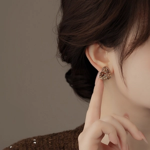 Close-up of vintage geometric gold stud earrings with amber rhinestones on a model