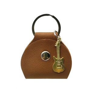 Close-up of brown leather guitar pick holder with a gold guitar charm and silver ring